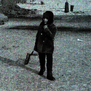 Child standing alone in snowy urban street.