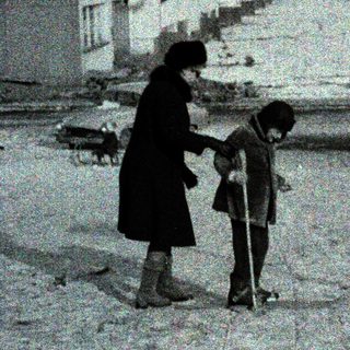 Snowy street scene with woman guiding child.