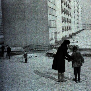Snowy urban street with woman and child holding hands.