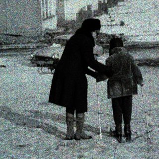 Snowy urban street with woman and child holding hands.