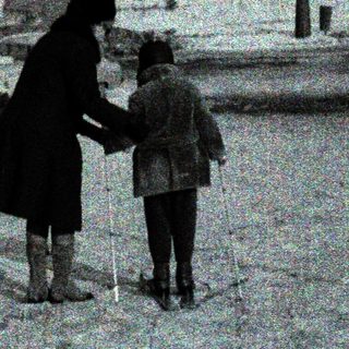 Snowy urban street with woman and child holding hands.