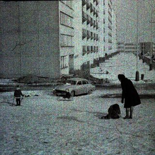 Snow-covered urban street with people clearing debris.