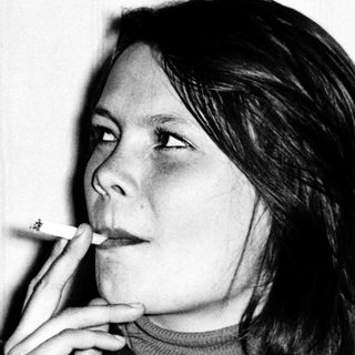 Two people sitting indoors, one smoking.