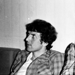 Two people sitting indoors, one smoking.