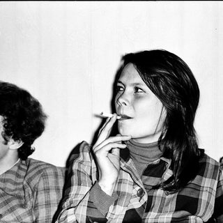 Two people sitting indoors, one smoking.
