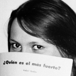 Person holds book with question "¿Quién es el más fuerte?" featuring strongman illustration.