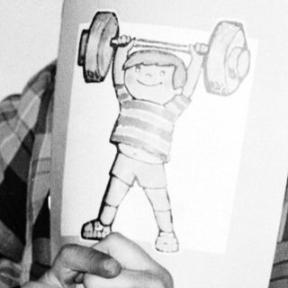 Person holds book with question "¿Quién es el más fuerte?" featuring strongman illustration.