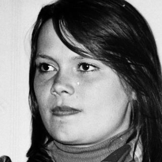 Young woman in plaid shirt posing indoors.
