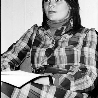 Young woman in plaid shirt posing indoors.