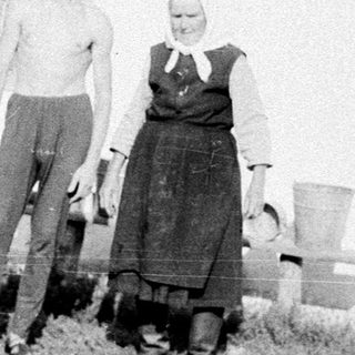 Two people posing outside a rural house.