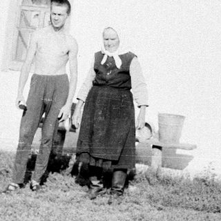 Two people posing outside a rural house.