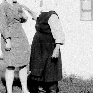 Two women painting exterior of a house.