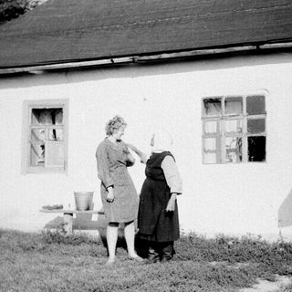 Two women painting exterior of a house.