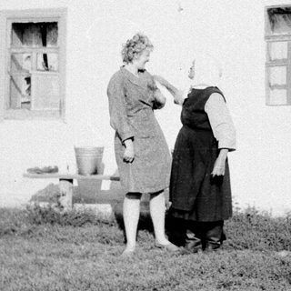 Two women painting exterior of a house.