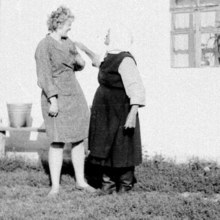 Two women painting exterior of a house.
