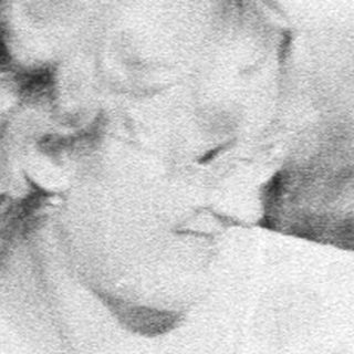 Two women and a child resting outdoors near a barn.