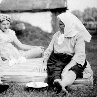 Three women sitting outdoors, mid-20th century.