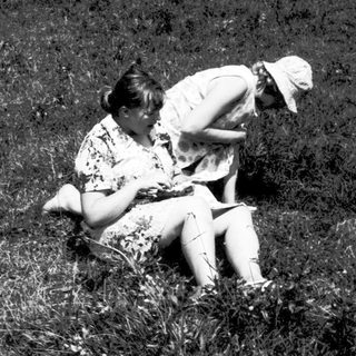 Two people sitting closely in grassy field.