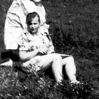 Two people sitting in muddy field.