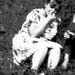 Two people sitting together outdoors in grassy field.