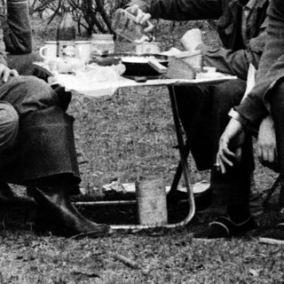 Three people camping, sharing a meal outdoors.