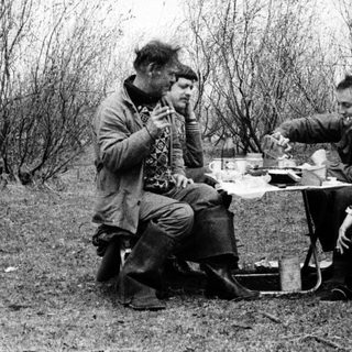 Three people camping, sharing a meal outdoors.