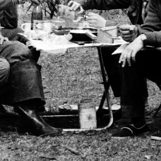 Two men camping, sharing a meal outdoors.