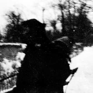 Two people embracing near a blurred waterfront.