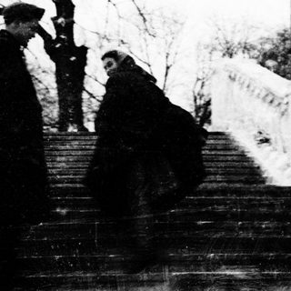 Two individuals descending snow-covered stairs in winter attire.