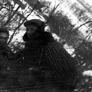 Two people in winter clothing walking through snow.