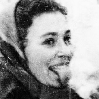 Two people sharing a cigarette outdoors in winter attire.