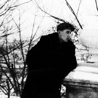 Two people standing near a gravestone in winter.