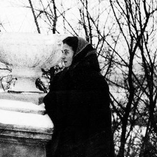 Two people standing near a gravestone in winter.