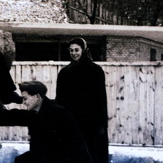 Two men interacting with a polar bear, winter setting, enclosed area.