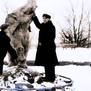 Two men inspecting a large elephant statue in snowy outdoor setting.