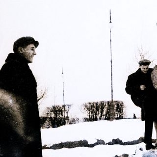 Two men standing beside a large elephant statue in snowy outdoor setting.