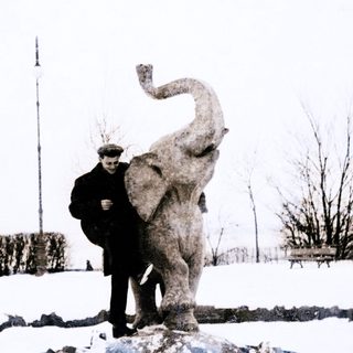 Two men standing beside a large elephant statue in snowy outdoor setting.