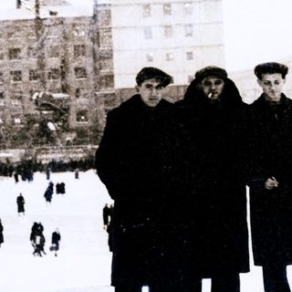 Winter city scene with ice skating rink and bundled-up people.