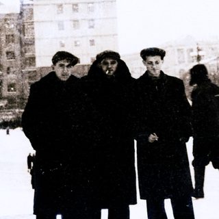 Winter city scene with ice skating rink and bundled-up people.