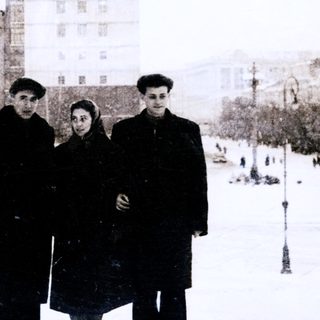 Three people posing in winter city square.
