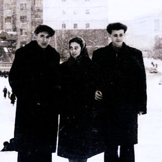 Three people posing in winter city square.