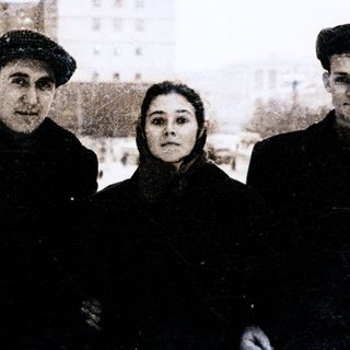Three individuals posing outdoors in winter clothing.