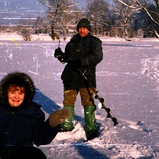 Two people ice fishing on a frozen lake.