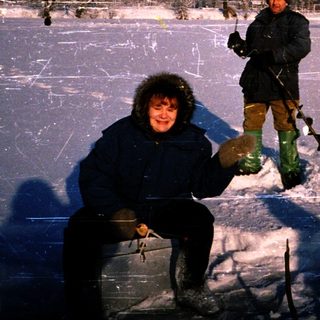 Two people ice fishing on a frozen lake.