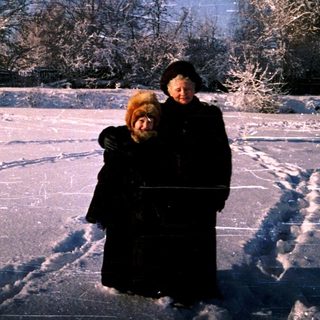 Two people embrace on a snow-covered ice rink under starry sky.