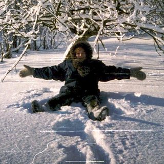 Person joyfully sledding down snow-covered hill.