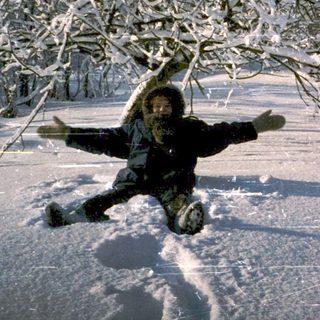 Person joyfully sledding down snow-covered hill.