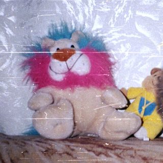 Two stuffed animals on a bed with a cat.
