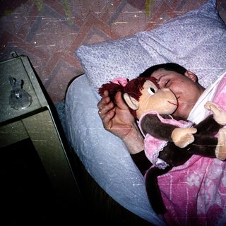 Child sleeping peacefully with stuffed monkey toy.