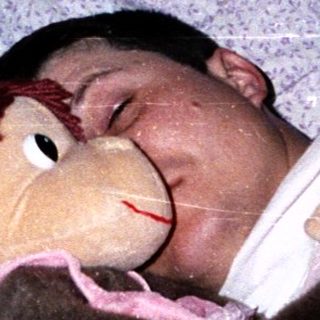 Child sleeping peacefully with stuffed monkey toy.